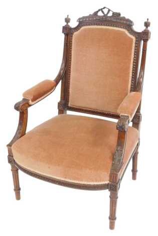 A Victorian mahogany open armchair, with carved back, overstuffed seat, back and arms, on turned and fluted legs.