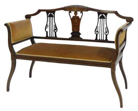 An Edwardian mahogany and marquetry salon sofa, the pierced back with cherub and instrument inlaid back, overstuffed seat and sides, on square shaped legs, 105cm wide.