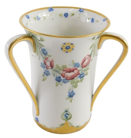 A Moorcroft Macintyre tyg vase, of slightly flared design with three stylised handles, having gilt outlines, the body decorated with tube lined floral swags in blue, and with flower head motifs in gilt, with gilt border, signed to the base and with mark f