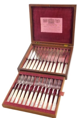 A set of twelve Victorian dessert knives and forks, with mother of pearl handles, in fitted mahogany case, with pink velvet linings, and label for Joseph Rogers & Sons of Sheffield, the lid inset with brass cartouche, 16cm x 22cm x 5cm.