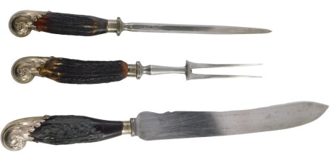 A late Victorian three piece carving set, with antler handles and silver plated scrolling acanthus leaf terminals, with silver ferrales.