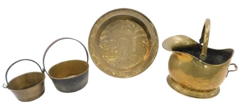 A large brass charger and other brass, comprising charger, brass helmet shaped coal scuttle, and two brass jam pans.