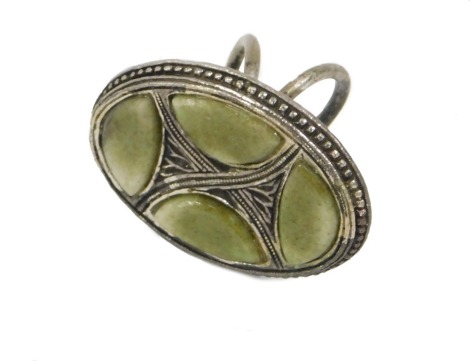 An Eastern inspired dress ring, the oval top set with green finish stones, in silver plated frame.