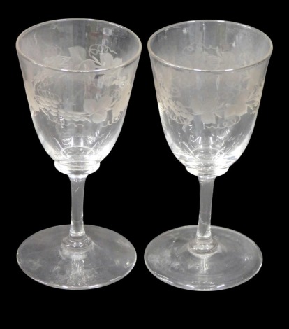 A pair of late Victorian wine glasses, engraved with fruiting vine decoration, on slender stems.