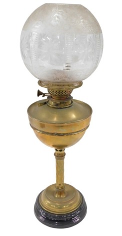 A Victorian brass oil lamp, the clear glass etched floral shade, on a brass reservoir and hatch stem, on a circular ebonised foot, 63cm high.