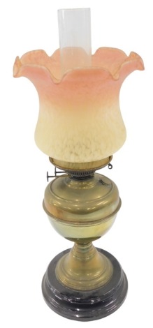 A Victorian brass oil lamp, the pink and yellow mottled shade, on a plain brass stem, on ebonised circular black foot, 58cm high.