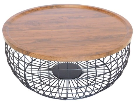 A Julian Bowen designer circular coffee table, with simulated oak tray shaped top, loose on a black metal basketwork base.