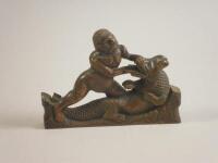 An 18thC walnut carving in the form of a semi naked figure wrestling a crocodile or alligator