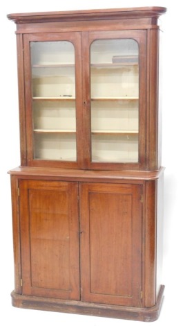 A Victorian mahogany bookcase, with plain moulded cornice to the upper glazed case, with three adjustable shelves enclosed by two glazed doors, stepped base with cupboard enclosed by two panelled doors and with plinth base, 206cm high, 107cm wide, 44cm de