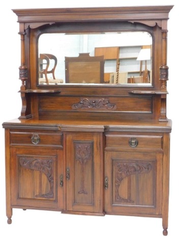 An Edwardian walnut mirror back sideboard, with moulded cornice to the canopy top, bevelled mirror and carved supports, the base with breakfront centre, having a central cupboard flanked by two cupboards, the carved panelled doors with Art Nouveau style c