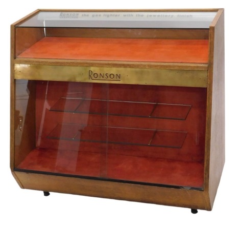 A Ronson Lighter glazed shop oak display cabinet, tapering design with upper glazed case having illuminated sign for Ronson Varaflame (The Gas Lighter The Jewellery Finish), brass Ronson plaque below above further glazed case with sliding glass doors, 100