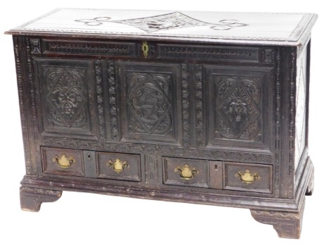 An 18thC carved oak mule chest, the hinged lid carved with a rampant lion, and gadrooned border, with three front panels having mask heads, above two drawers, raised on bracket feet, 85cm high, 127cm wide, 52cm deep.