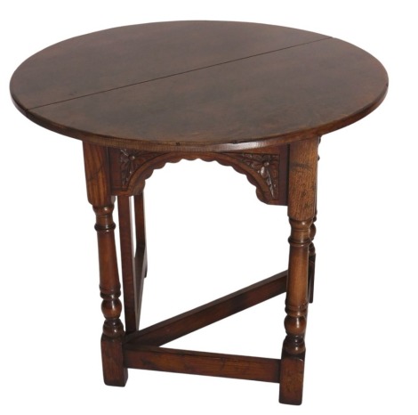 A stained oak gate leg occasional table, with single four leaf top, carved arcaded frieze, and turned legs and plain stretchers, 69cm high.