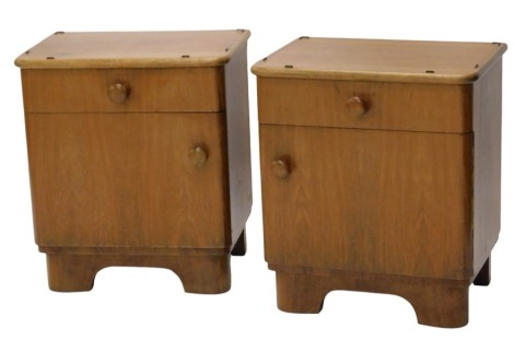 A pair of mid 20thC teak bedside cupboards, each fitted with a drawer and with cupboards below having plain knop handles, and with stylised bracket feet, lacking plate glass tops, 60cm high, 53cm wide.