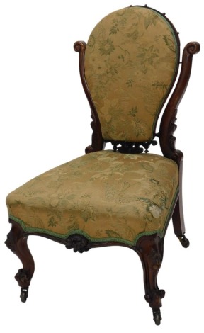 A Victorian mahogany low seated nursing chair, with scroll supports to the pivoting padded back, over upholstered seat, on fancy carved French cabriole legs with castors.