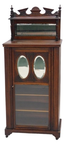 A music cabinet, with broken arched gallery top, mirror below, the interior with shelves and enclosed by a twin mirrored partially glazed single door, on pot castors, 127cm high, 54cm wide.