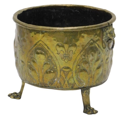 A brass log bin, with lion ring handles embossed with fleur de lys and supported on three lion's paw feet, 45cm diameter.