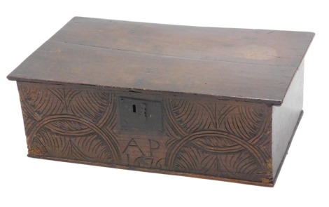 A 17thC oak Bible box, with plain hinged lid, the front with iron lock plate and carved intertwined archaedic decoration and initialled AP, 27cm high, 64cm x 38cm.