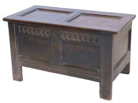 A late 17thC small oak coffer, with double panelled hinged lid and double panelled front with gouged frieze and carved decoration, on stile legs, 97cm wide.