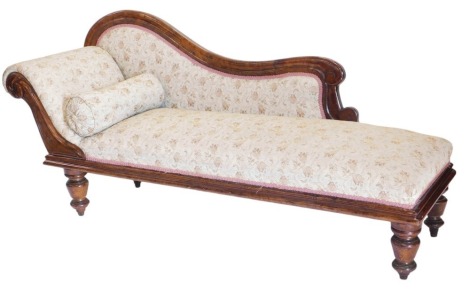 A Victorian rosewood framed chaise longue, with padded scroll back and arm, carved decoration to the front raised on turned legs with castors.