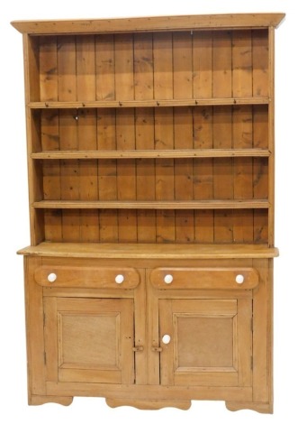 A pine open dresser, with plain cornice to the upper section, and fitted three shelves to the open back, the base fitted two drawers and with cupboards below having panelled doors, 101cm high, 134cm wide.