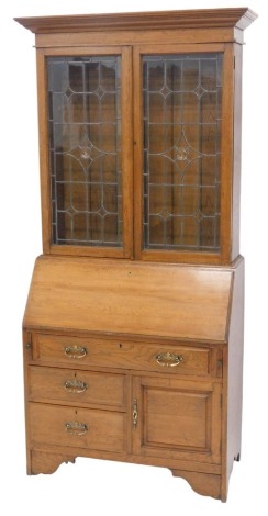 A 1920s oak bureau bookcase, the glazed upper section with moulded cornice, and with glazed cabinet below having leaded light doors, fitted interior to the bureau section, and with three drawers, and a cupboard, on bracket feet, and end supports, 204cm hi