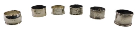 A group of six various Edward VII and later silver napkin rings, two of engraved design bearing the initials MMG, and three plain, one with rope twist border, 4.48oz.