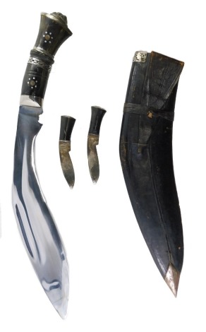 A 20thC kukri knife, the horn handle set with silvered markers, and two miniature knives, in a leather scabbard, the blade engraved by design, 43cm wide.