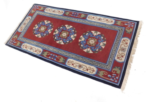 A Nepal rug, on a red ground, with geometric borders, bears label, 180cm x 93cm.