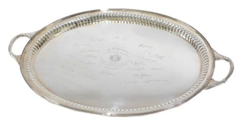 A George V silver two-handled presentation tray, of oval design with reeded fluted border, inscribed to M C Wylie Esq. by His Brother Officers of The Rangoon Pilot Service with facsimile signatures 1934, Sheffield 1933, makers Roberts & Dore Ltd, 76oz, 60