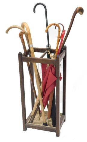 A 20thC oak stick stand, and various parasols and walking sticks, the stand 69cm high, 30cm wide, 25cm deep.