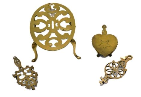 Victorian brass trivets, including a large oval trivet with pierced scroll design platform, on four stylised cabriole legs, and three small brass hand trivets.