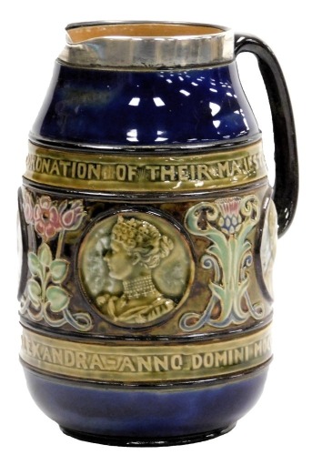 An early 20thC Doulton Lambert stoneware commemorative jug, for the Coronation of their Majesties King Edward VII, and Queen Alexandra 1902, decorated with a central band, with four profile roundels, interspersed by Art Nouveau flowers, with a silver moun