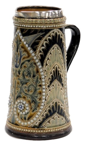 A late 19thC Doulton Lambeth stoneware jug, with silver mount, moulded and sgraffito decorated with repeating flower heads and trailing leaves, with white jewelling, impressed and incised marks, factory mark lacking, London 1882, 24cm high.