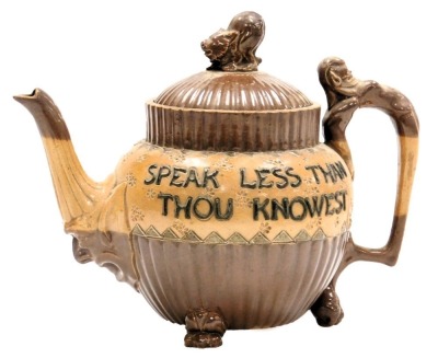 A late 19thC Doulton Lambeth stoneware two tone teapot, of fluted form, the lid with an animal finial, spout with a mask head terminal, and handle topped with a grotesque, the body decorated with "Speak Less Than Thou Naowest, Have More Than Thou Showest"