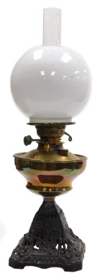 A late 19thC brass and cast iron oil lamp, with a brass reservoir, chimney and white glass shade, 57cm high.