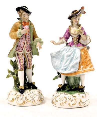 A pair of 20thC Continental porcelain figures, modelled as a gallant and lady, each raised on a rococo scroll base, blue crossed swords marks, 24cm high. (AF)