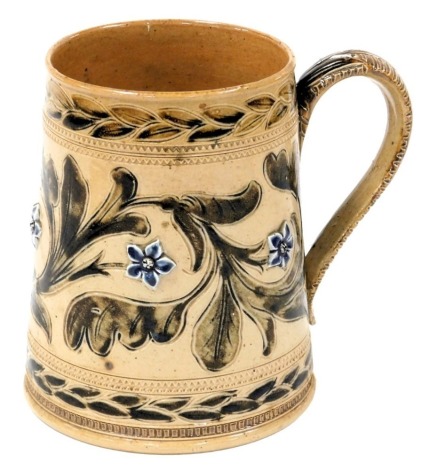 A late 19thC Doulton Lambeth stoneware tankard, designed by Arthur B. Barlow, moulded and sgraffito decorated with flowers and scrolling leaves, against a buff ground, dated 1873, impressed and incised marks, 17.5cm high.