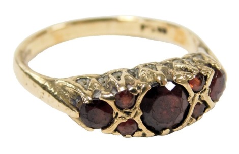 A 9ct gold and garnet set ring, with three principle garnets flanked by two pairs of smaller garnets, size N, 2.9g.