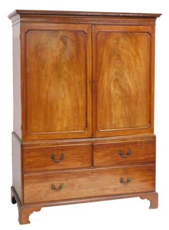 A George III mahogany linen press, the out swept pediment over a pair of panelled doors enclosing a later interior, above two long graduated drawers, raised on bracket feet, 200cm high, 147cm wide, 64cm deep.