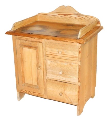 A Victorian style pine wash stand, with a galleried top, above a single door flanked by three drawers, raised on stiles, 84cm high, 73cm wide, 48cm deep.