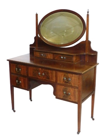 An Edwardian mahogany and line inlaid dressing table, the oval swing frame mirror inset bevelled glass, within a frame of two frieze drawers, the base with one long and four short drawers, raised on tapering square legs, brass capped on castors, 147cm hig