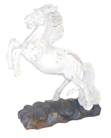 A painted wooden carving of a rearing horse, raised on a naturalistic base, 102cm high, 74cm wide.