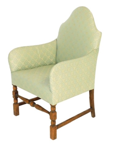 An early Georgian style oak nursing chair, upholstered in green foliate fabric, raised on turned legs united by a turned front stretcher, 54cm wide.