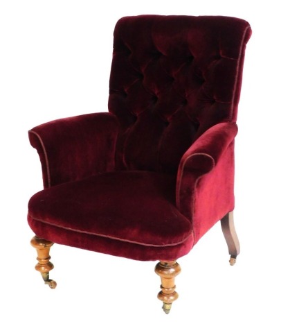 A Victorian mahogany nursing chair, upholstered in red button back fabric, raised on turned legs, brass capped on castors, 80cm wide.