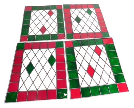 Four stained glass window panels, with green, red and clear panels, 95.5cm x 85cm, 95cm x 81cm, 95cm x 80cm, and 97cm x 82cm.