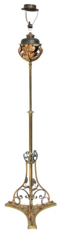 A Victorian copper and brass gasolier standard lamp, converted to electricity, with a open work leaf scroll reservoir holder, on a turned column, above a tripod base, with scroll supports, 178cm high.