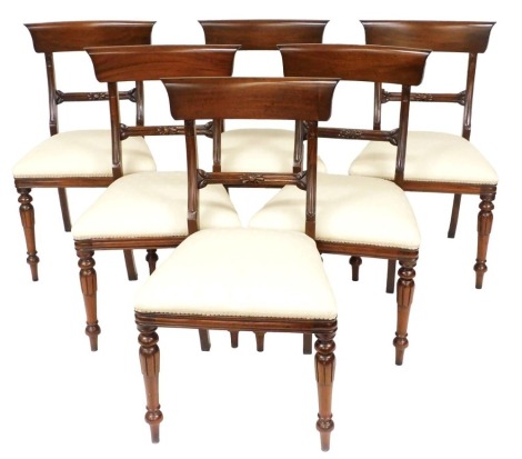 A set of six Regency style mahogany bar back dining chairs, with cream overstuffed seats, raised on lappet carved legs.