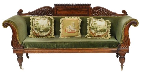 A late Regency mahogany sofa, with a leaf scroll back, and scroll arms, upholstered in green fabric, raised on turned legs, brass capped on castors, 209cm wide.