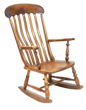 A Victorian oak and elm lath back rocking chair, with a solid saddle seat, raised on turned supports, 59cm wide.